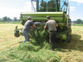 Picture of two men clearing a blockage on a harvester